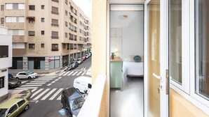 A hotel room with a bed, a small table, and a window.