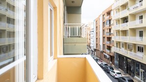 A narrow balcony with a view of a street and adjacent buildings.