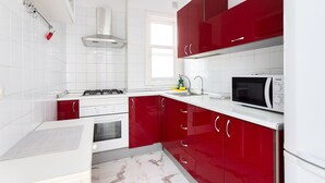 A modern kitchen with white and red cabinetry, a gas stove, a microwave, and a window providing natural light.