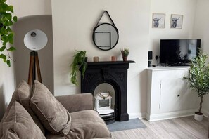 A living room with a sofa, a fireplace, a television, and a potted plant. - Cottage - Sleeps 4 - Pets Ok - Garden - Parking (Middlewich)