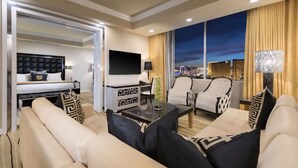 Une chambre d’hôtel moderne dotée d’un grand lit, d’une télévision, d’un coin repas et offrant une vue sur le paysage urbain au crépuscule.
