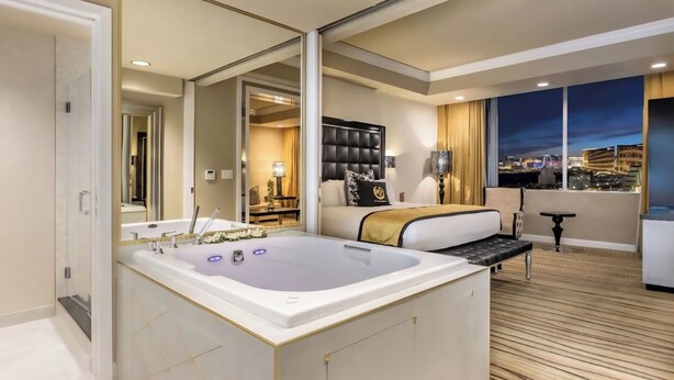 Une chambre d’hôtel moderne dotée d’une grande baignoire, d’un canapé-lit, d’une table à manger et offrant une vue sur la ville.