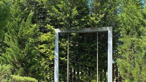 A wooden swing set under a white metal frame, surrounded by lush greenery and a paved pathway. - Private Pool Villa • 4BR •Fast Wifi • Koh Chang (Tambon Ko Chang)