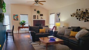 A living room with two sofas, a coffee table, a fireplace, and a ceiling fan. - Private room in a Beautiful house Centrally Located  (Denton)