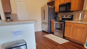 A modern kitchen with wooden cabinets, stainless steel appliances, and a white countertop. - Private room in a Beautiful house Centrally Located  (Denton)