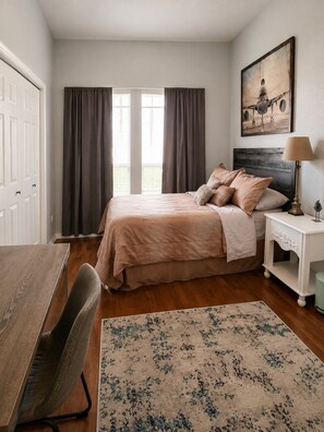 A bedroom with a bed, a bedside table with a lamp, a chair, a desk, and a window with curtains. - Private room in a Beautiful house Centrally Located  (Denton)