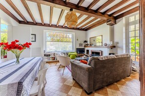Una habitación con una mesa de comedor, sillas, un sofá, una lámpara colgante y una chimenea.