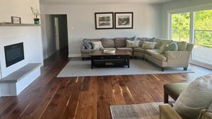 A modern living room with a sectional sofa, a fireplace, and framed artwork on the wall. - Tranquil Lakefront Cottage (Greater Napanee)