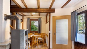 Un comedor con mesa y sillas, una chimenea, techo de madera y una puerta con vidrio esmerilado.