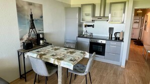 A compact kitchen with a dining area, featuring a coffee maker, a kettle, and a small oven.