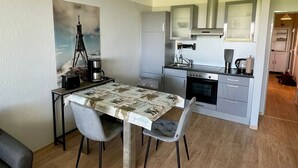 A compact kitchen with modern appliances, a dining area with a table and chairs, and a small seating area with a sofa.