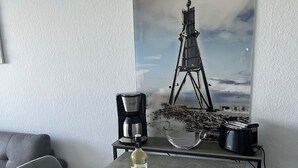 A dining area with a table, chairs, a coffee maker, a bottle, and a snack packet.