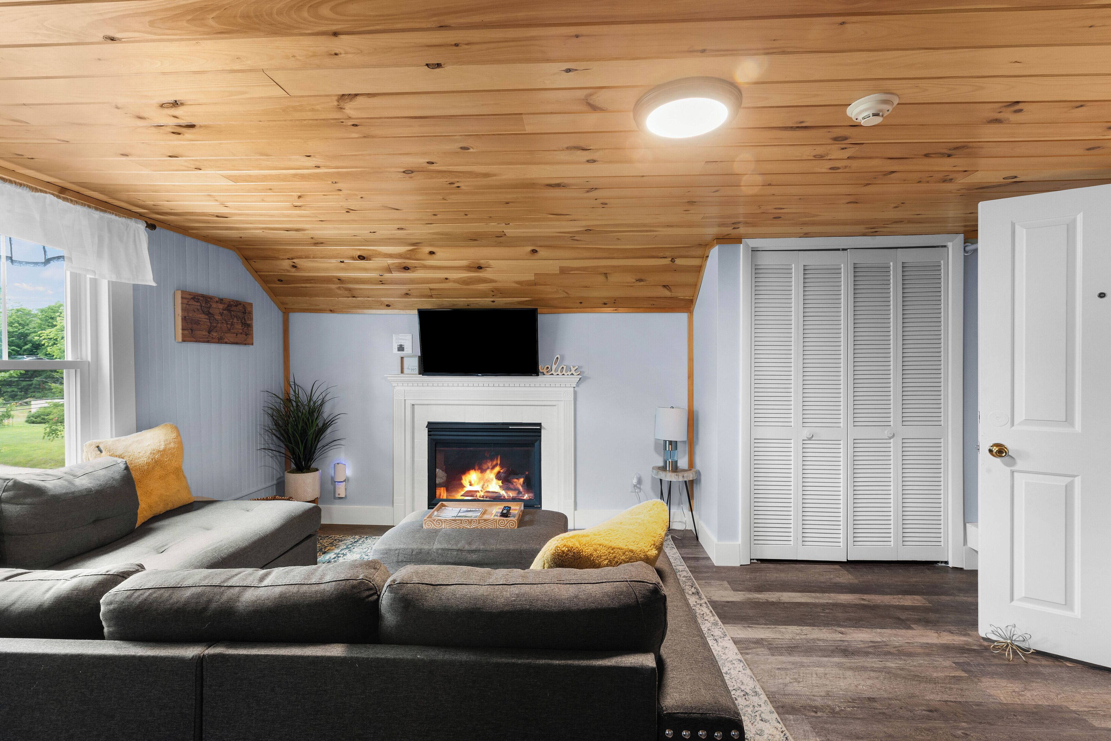 Un salón acogedor con chimenea, techo de madera y vistas al exterior.