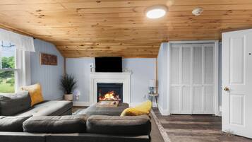 Un salón acogedor con chimenea, techo de madera y vistas al exterior.