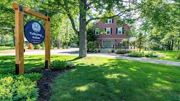 A sign for Tuckaway Suites, a brick building with a green lawn and trees.