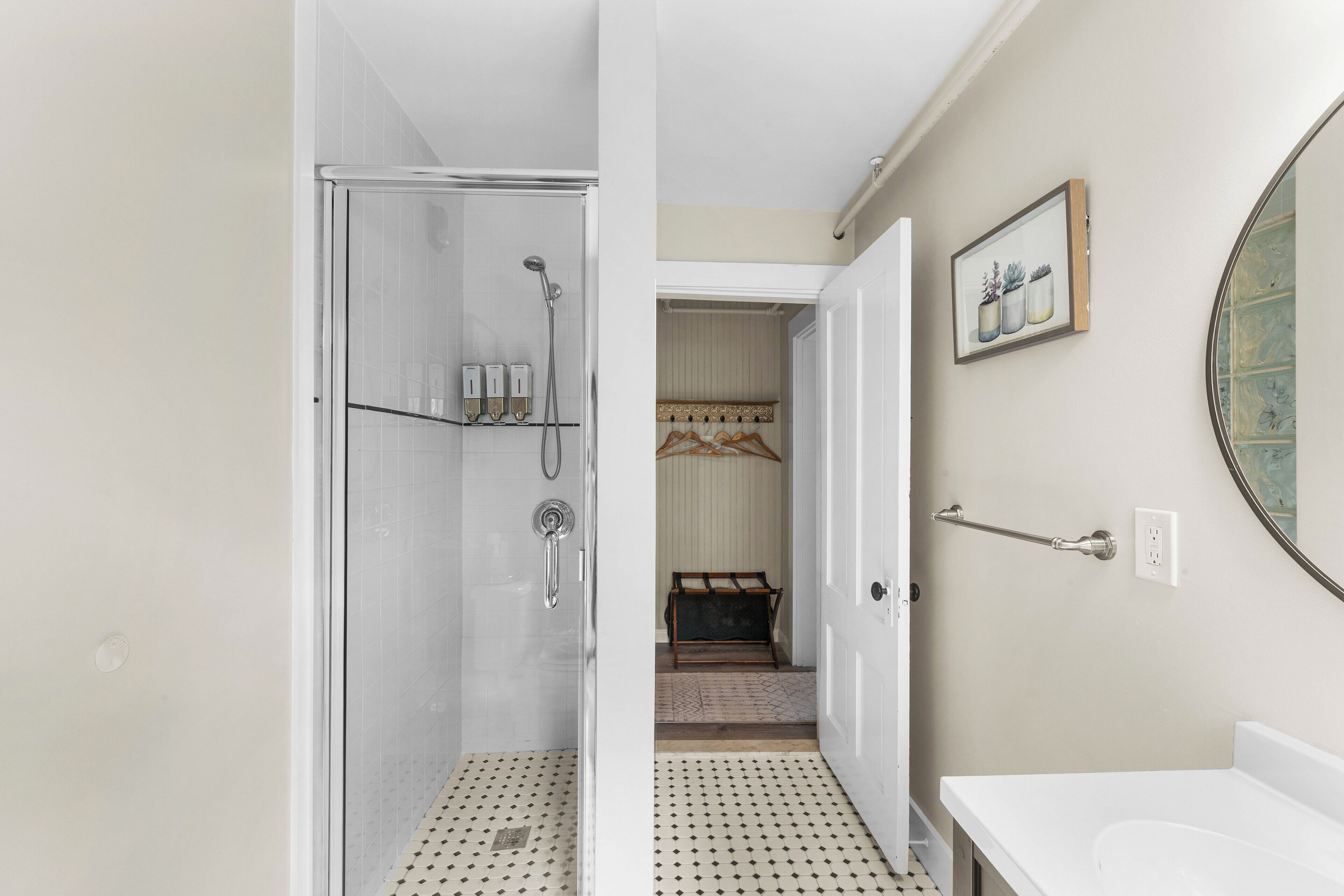 A bathroom with a shower, a sink, and a mirror.