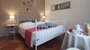A neatly arranged bedroom with a bed, bedside tables, a small table with breakfast items, and a wall-mounted mirror.