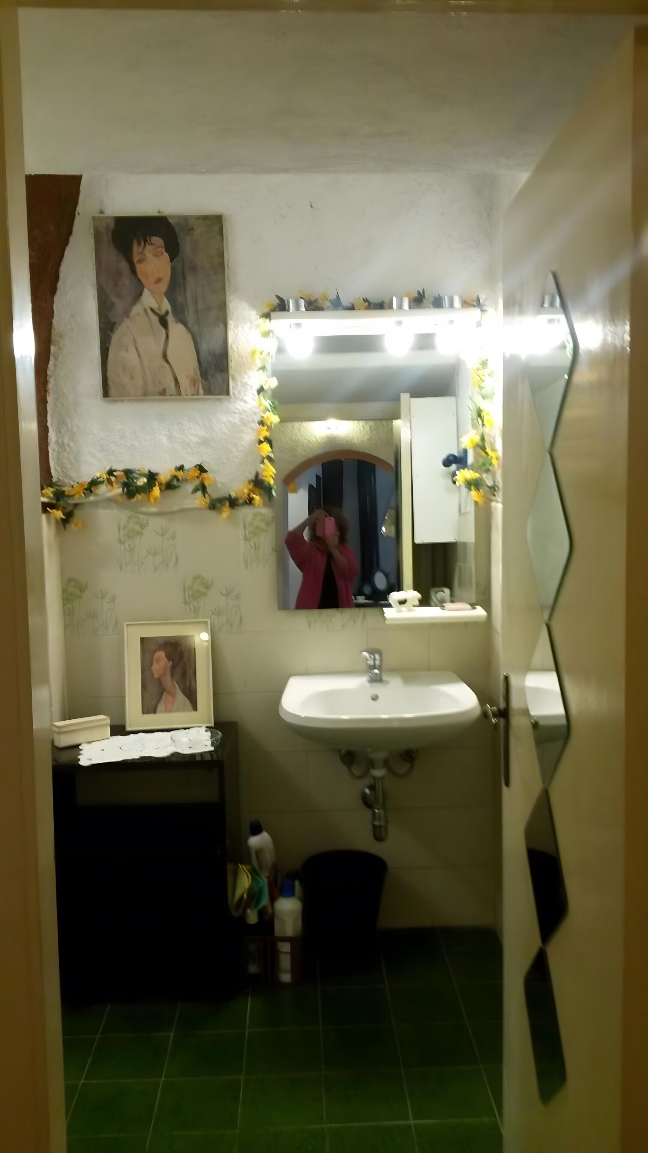 Un baño con lavamanos, espejo y un cuadro en la pared.