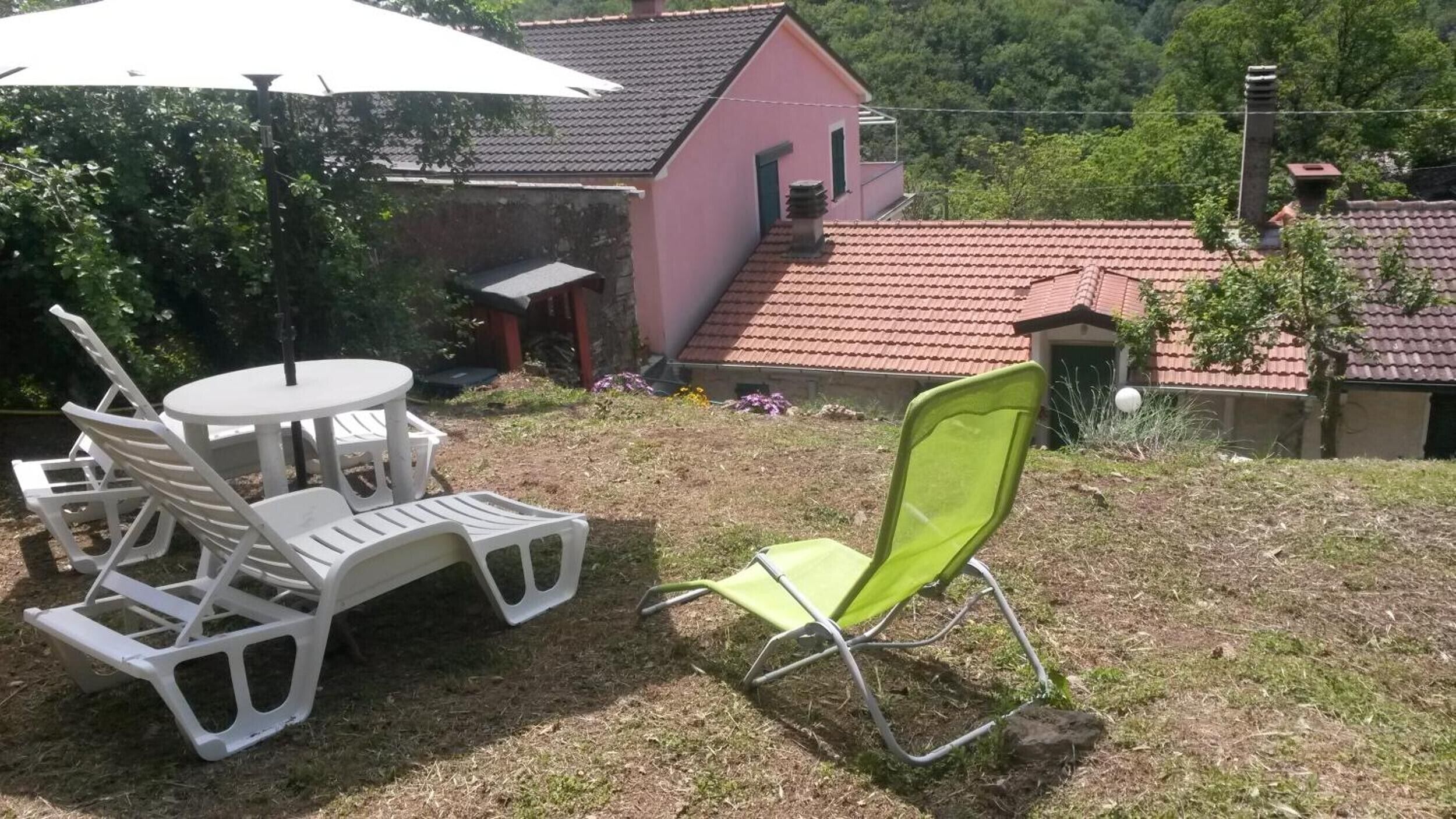 A patio with a table and chairs, a green chair, and a white umbrella.