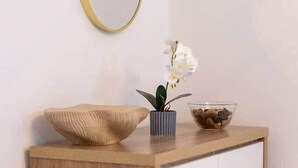 A wooden dresser with a mirror, a bowl of pebbles, and a potted orchid. - Pleasant Studio in St Albans (St Albans)