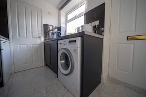 A compact kitchen with a built-in washer and dryer, a window, and a door.