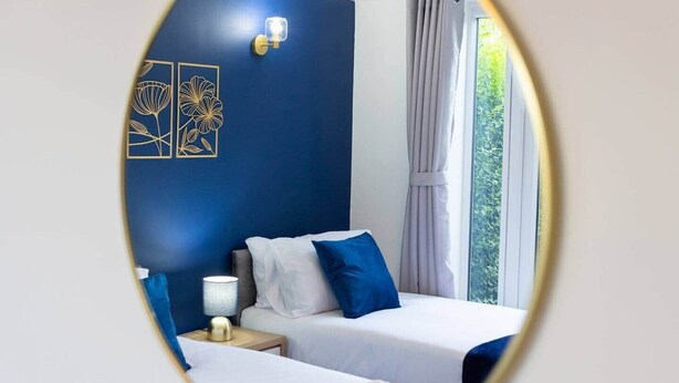 A hotel room with two beds, a nightstand, a lamp, and a window with curtains. - Pleasant Studio in St Albans (St Albans)