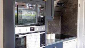 A modern kitchen with a built-in microwave, oven, and a stainless steel range hood.