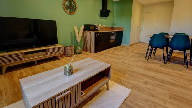 A modern living room with a flat-screen TV, wooden coffee table, and blue chairs. - A haven of peace near Pérouges, charm and comfort (Faramans)