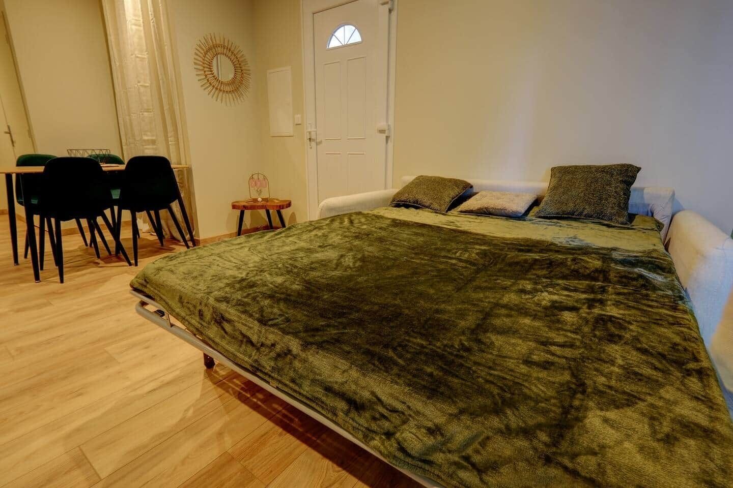 A bedroom with a bed, a desk, chairs, and a small table.