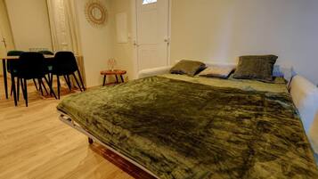 A bedroom with a bed, a desk, chairs, and a small table.