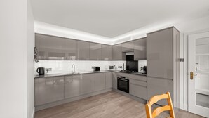Une cuisine moderne équipée d’appareils électroménagers en acier inoxydable, d’une table à manger en bois et d’un four encastré.
