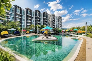 Um hotel moderno com piscina, espreguiçadeiras e guarda-sóis.