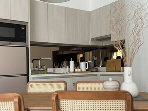 Uma cozinha moderna com micro-ondas, fogão e área de refeições com cadeiras.