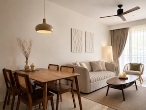 A modern living room with a dining area, a sofa, a coffee table, and a ceiling fan.