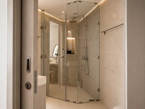 Een moderne badkamer met een douchecabine van glas, marmeren tegels en een zichtbare wastafelruimte.
