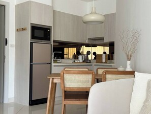 A modern kitchen with built-in appliances, a dining area with wooden chairs, and a white sofa.