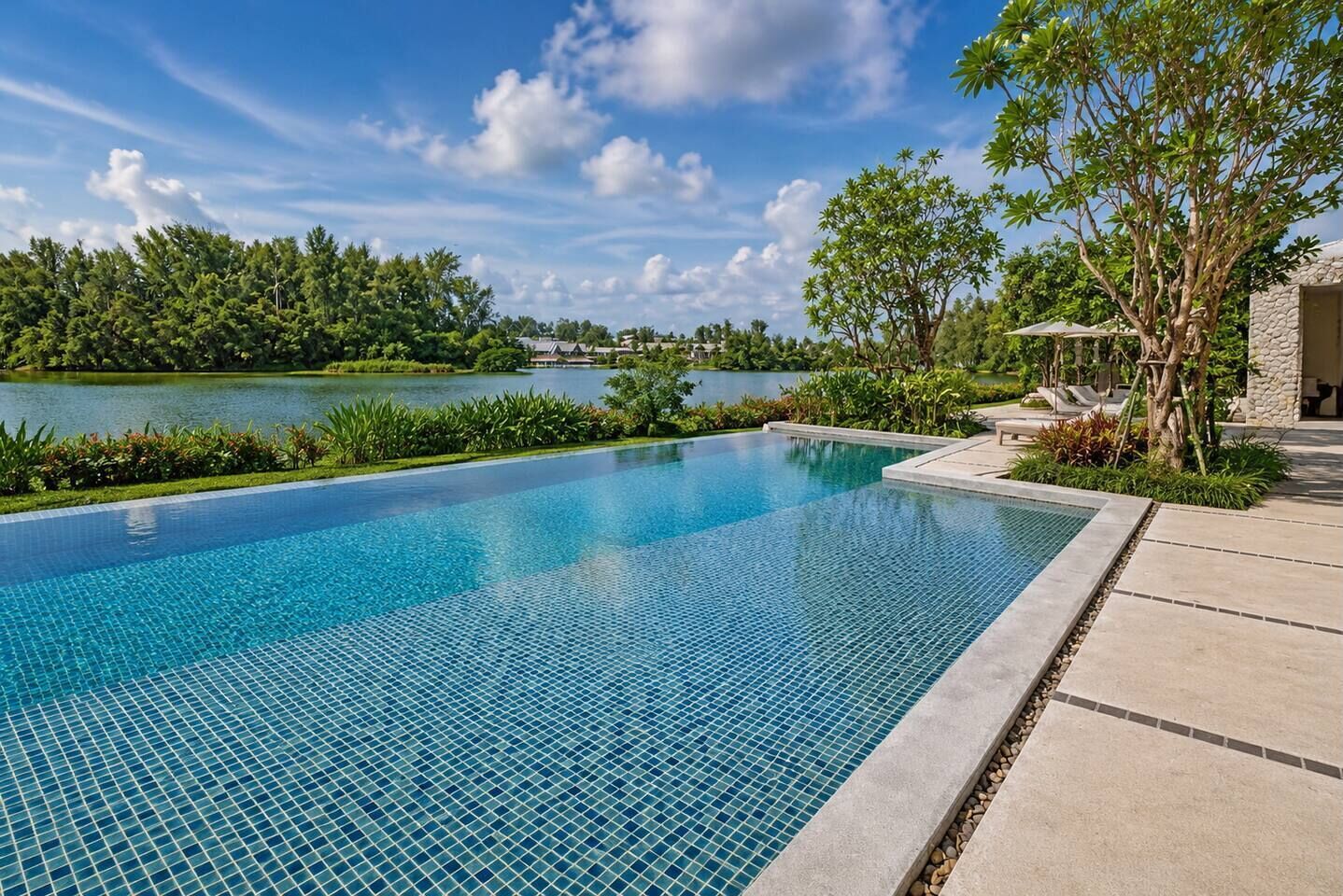 Uma piscina infinita azul límpida com vista para um lago e árvores.