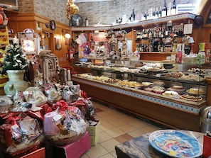 A bakery with a variety of baked goods on display, a bar area with bottles, and a Christmas tree decoration. - Station Accommodation (Naples)