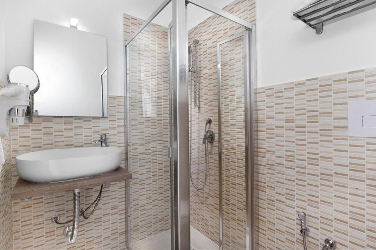 A modern bathroom with a glass-enclosed shower, a white sink, and a tiled backsplash.