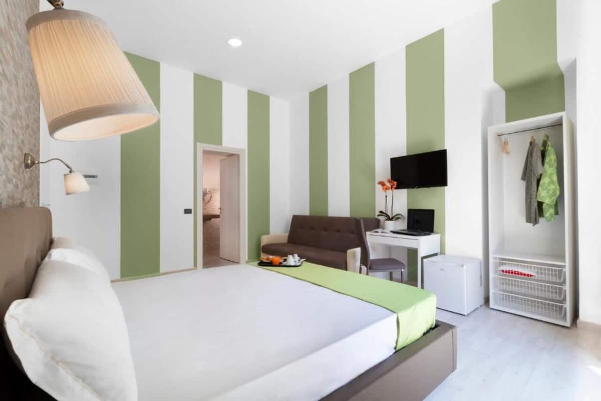 A bedroom with a bed, a desk, a chair, a television, and a wardrobe.