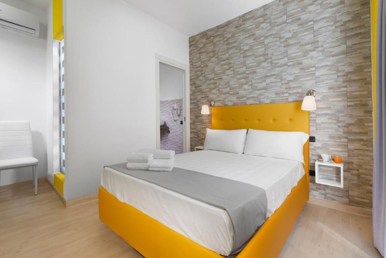 A modern bedroom with a large bed, a bedside table, and a wall-mounted light fixture.