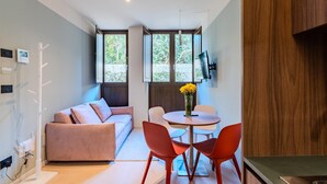 Ein stilvoller Wohnraum mit einer Couch, einem Esstisch mit Stühlen und einem an der Wand befestigten Fernseher.