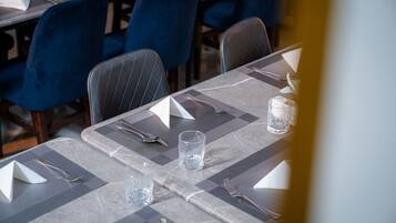 Ein Esstisch mit Platzsetting, Besteck und einem Glas Wasser.