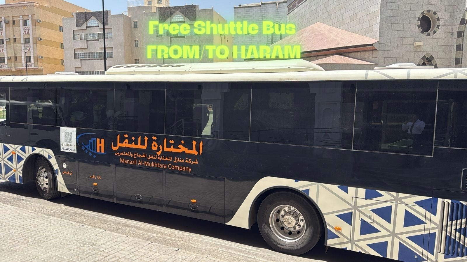 Een shuttlebus met de tekst 'Gratis shuttlebus NAAR VANDAAN HARAM' en de branding van 'Manazil Al-Mukhtar Company'.