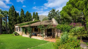 A house with a stone facade, a tiled roof, and a well-maintained lawn. - Villa 'Reco Vert' with Mountain View, Private Pool and Air Conditioning (Pollença)