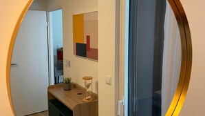 A round mirror reflecting a room with a wooden counter, a potted plant, and a wall-mounted artwork. - Zenao Appart'hôtels Tours (Tours)