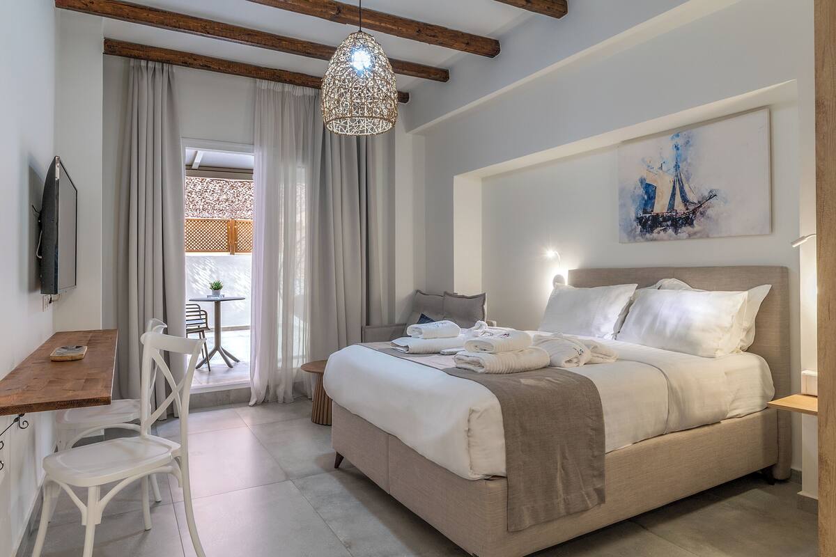 A bedroom with a bed, bedside table, and a hanging light fixture.