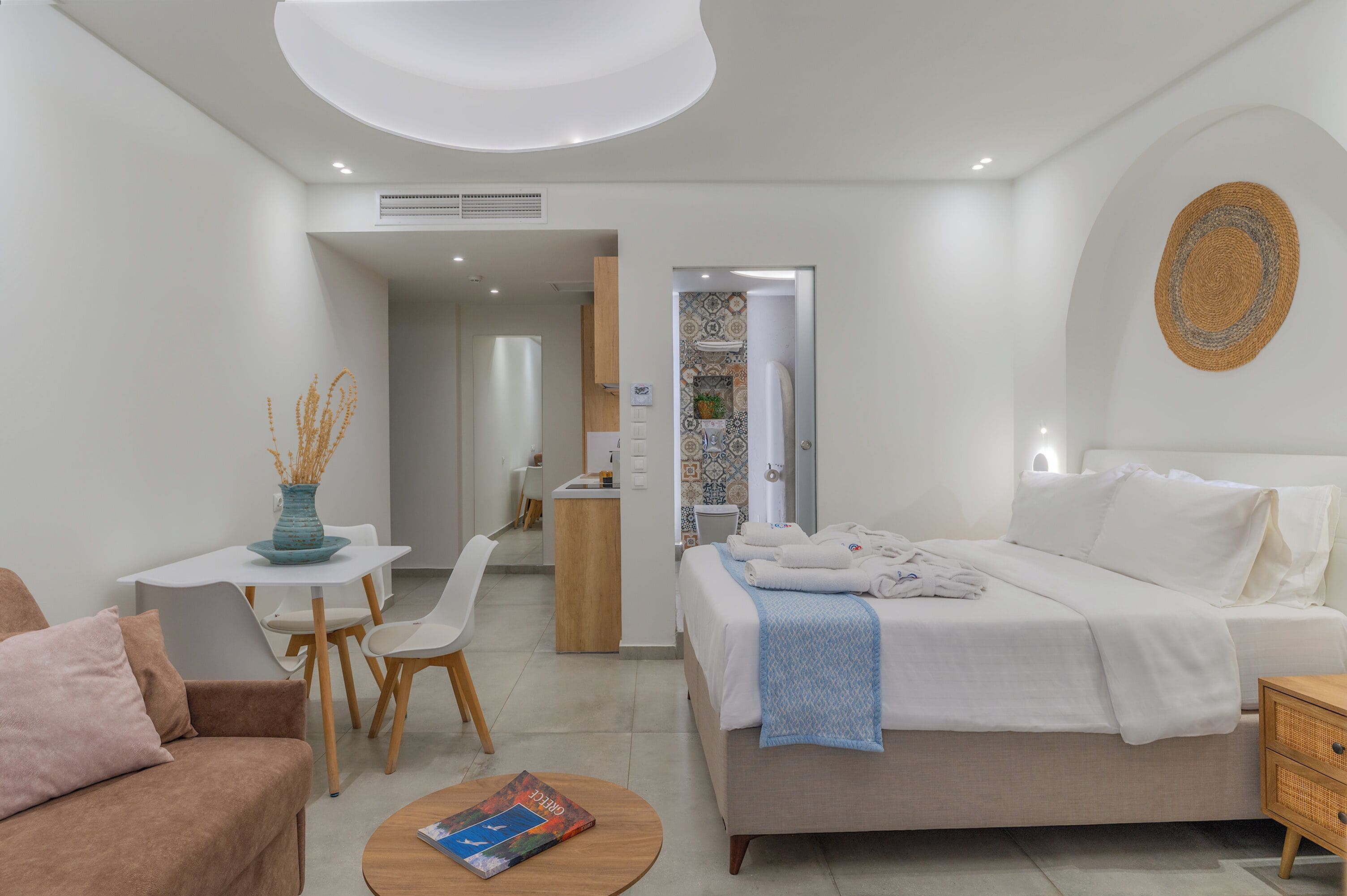 A modern hotel room with a bed, a desk, a chair, and a small table.