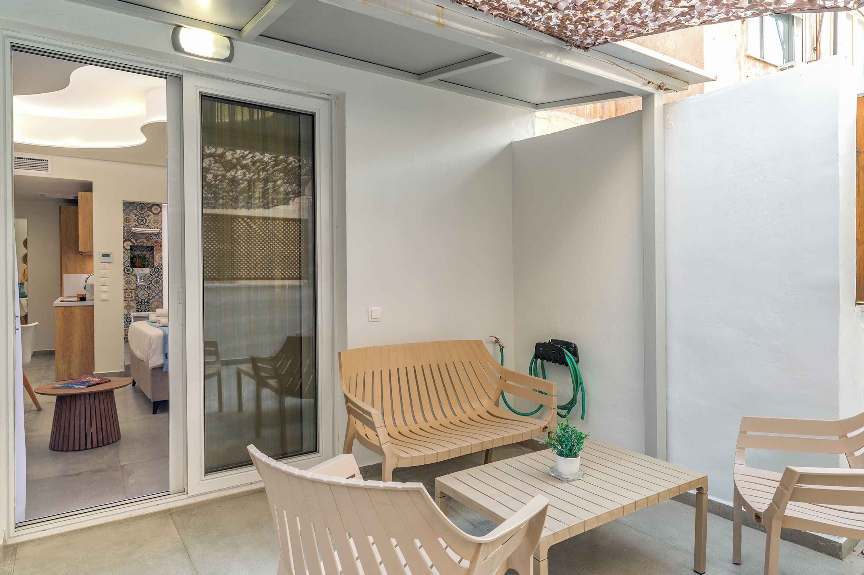 Un patio moderno con un banco de madera, una mesa y una planta en maceta.