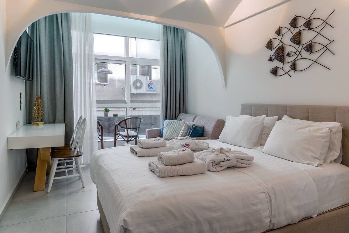 A hotel room with a bed, a desk, a chair, and a window with curtains.